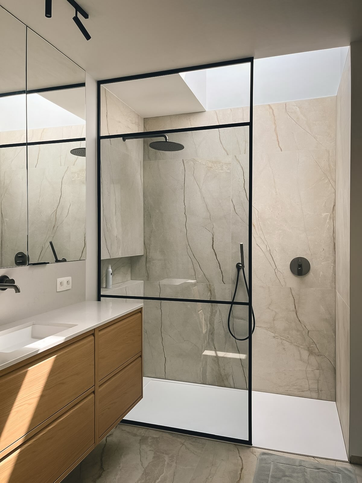 Douchewand in zwart staal en helder glas in een badkamer met marmerlook