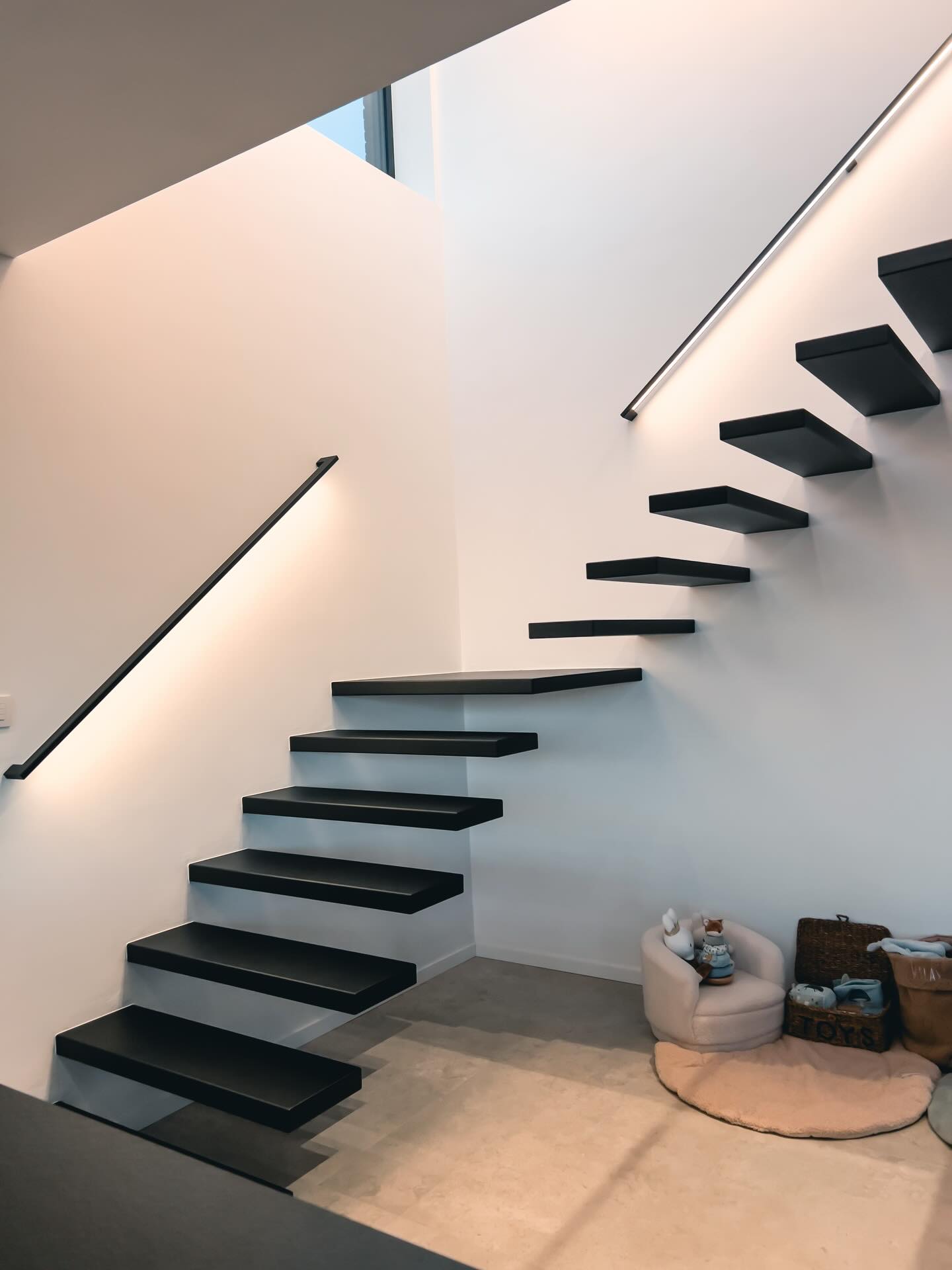 Zwevende trap in zwart staal met ledleuning